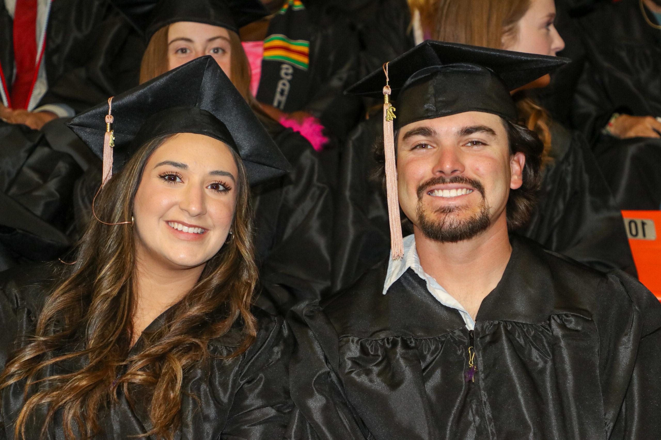 Man and woman sitting side by side in graduation attire